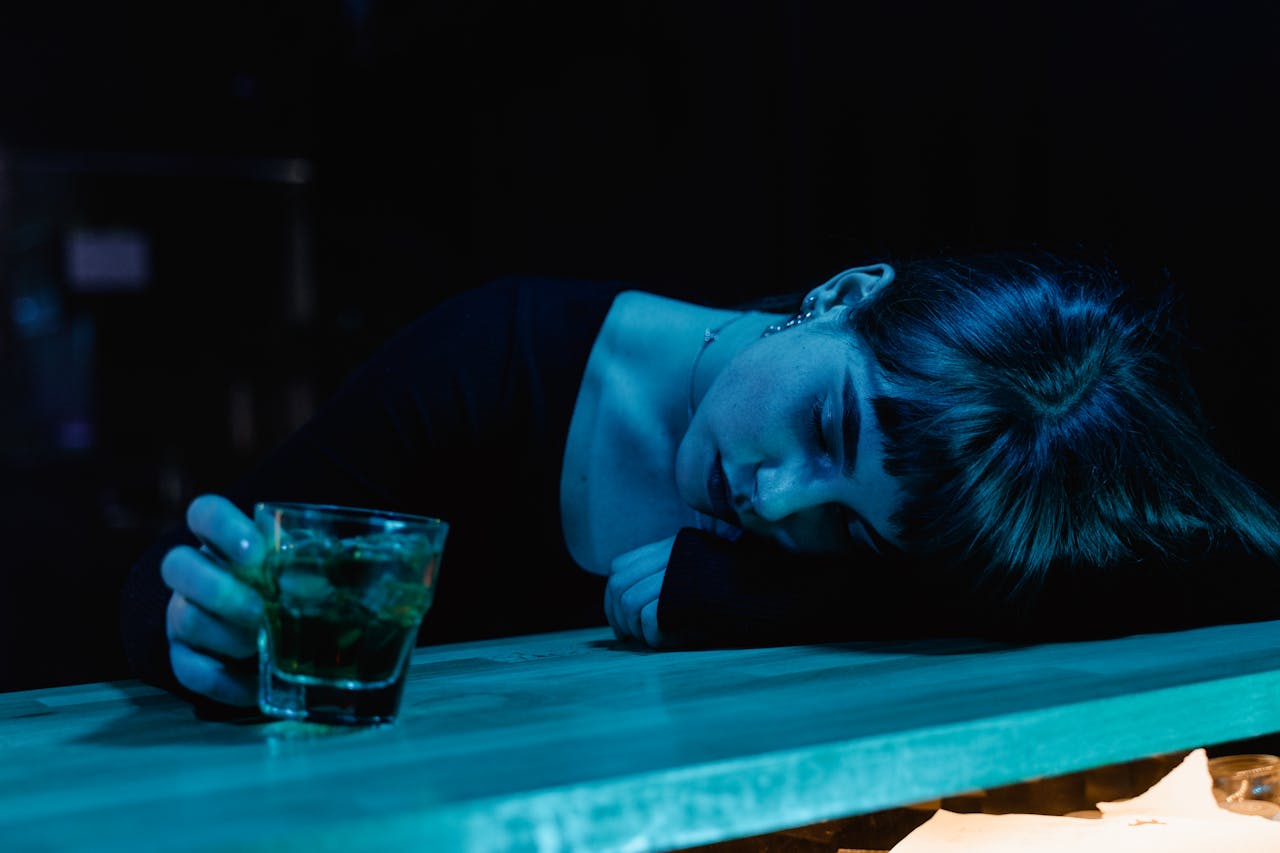 Woman lying on the bar and drinking a cocktail which means nobody recognized her addiction relapse warning signs