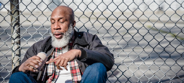 An older man drinking instead of reading the best books about sobriety