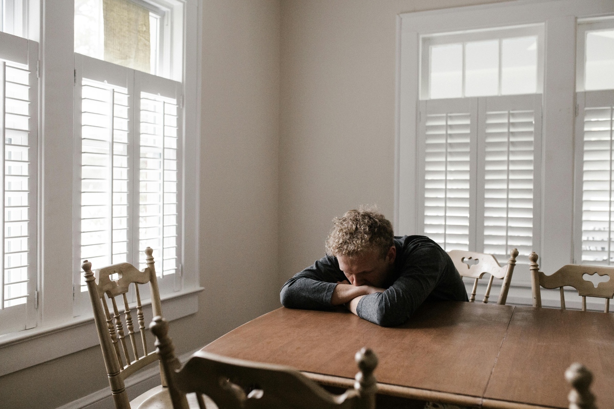 A man is sitting with his hands over the table, dealing with marijuana and panic attacks.