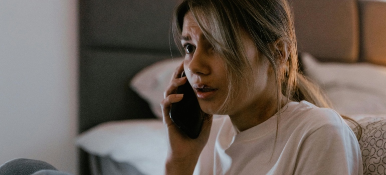 A woman sitting next to the bed and talking on the phone about marijuana and panic attacks.