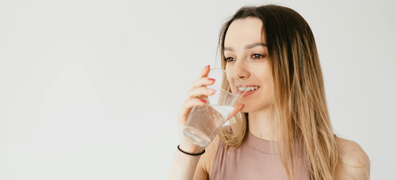 A woman is drinking water from a glass.