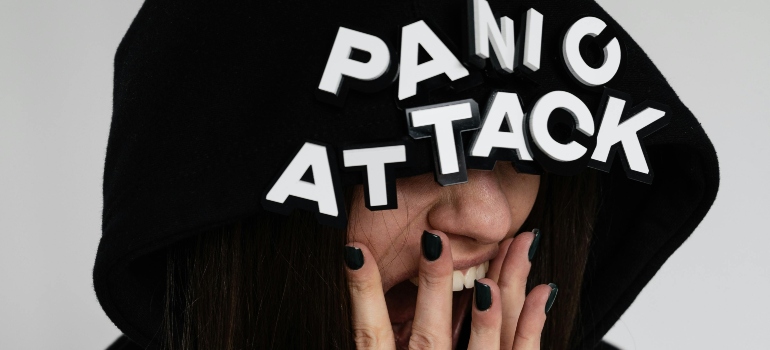 A woman wearing black hoodie having a panic attack.