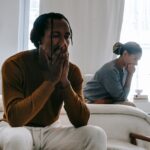 Unhappy couple sitting on bed after having an argument.