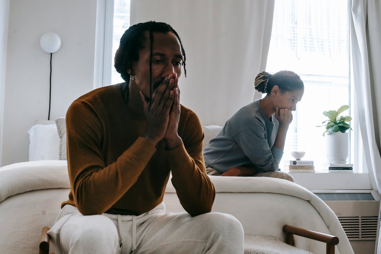 Unhappy couple sitting on bed after having an argument.