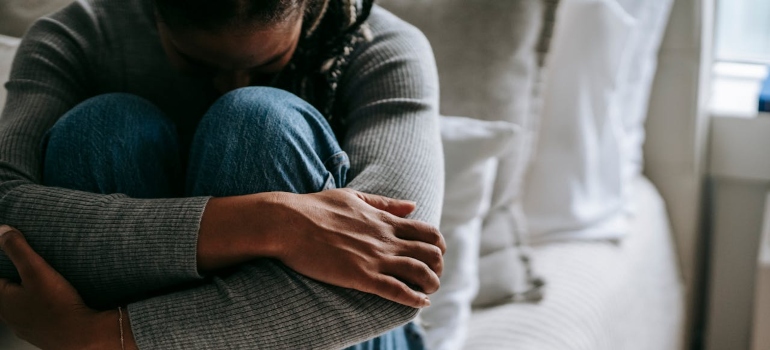 Woman hugging her knees to her chest worrying about prescription drug abuse on the rise.