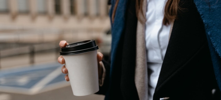 a woman carrying a take out coffee 