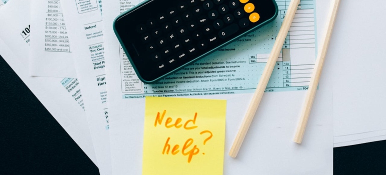 Phone on top of documents and a "need help" sign