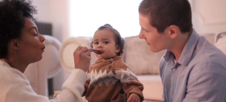 Mother feeding a child trying to navigate co parenting with a drug addict.