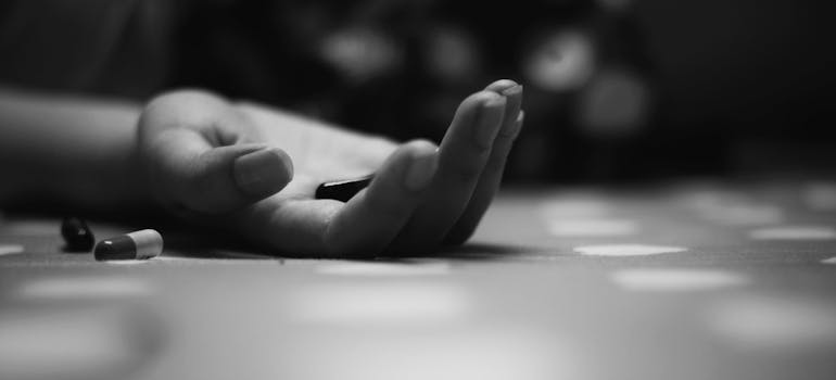 Person's hand holding pills on the floor.