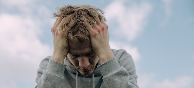 Man holding his head while dealing with OCD and addiction treatment.