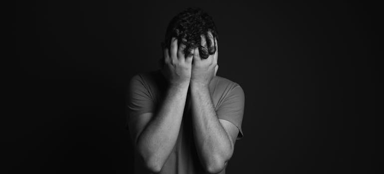 Black and white picture of a man covering his face while struggling with heroin addiction and bipolar disorder.