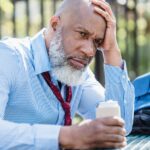 Older man holding a beer can and dealing with binge drinking and depression.