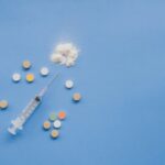 Syringe surrounded by pills and white powder.