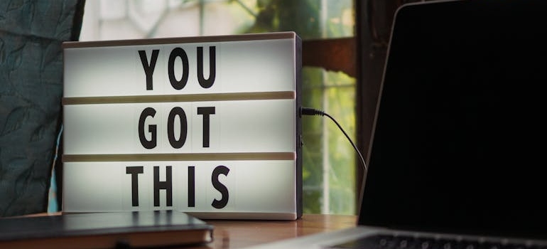 Light up sign spelling 'You got this' next to a laptop.