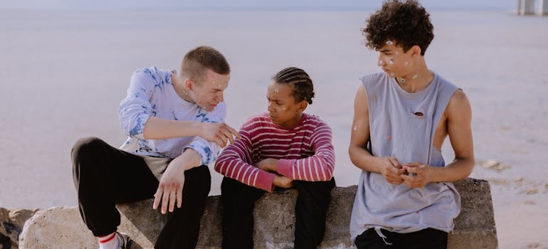 Group of teens sitting on a rock and discussing inhalant abuse.