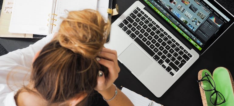 Woman holding her head while looking at her laptop.