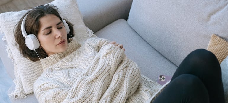 Woman lying on the couch and wearing headphones.