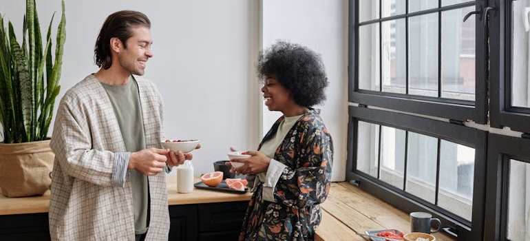 Man and woman standing in the kitchen and laughing.