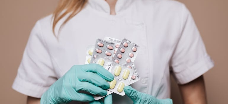 Female doctor holding blisters of pills.