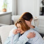 Woman crying and hugging another woman.