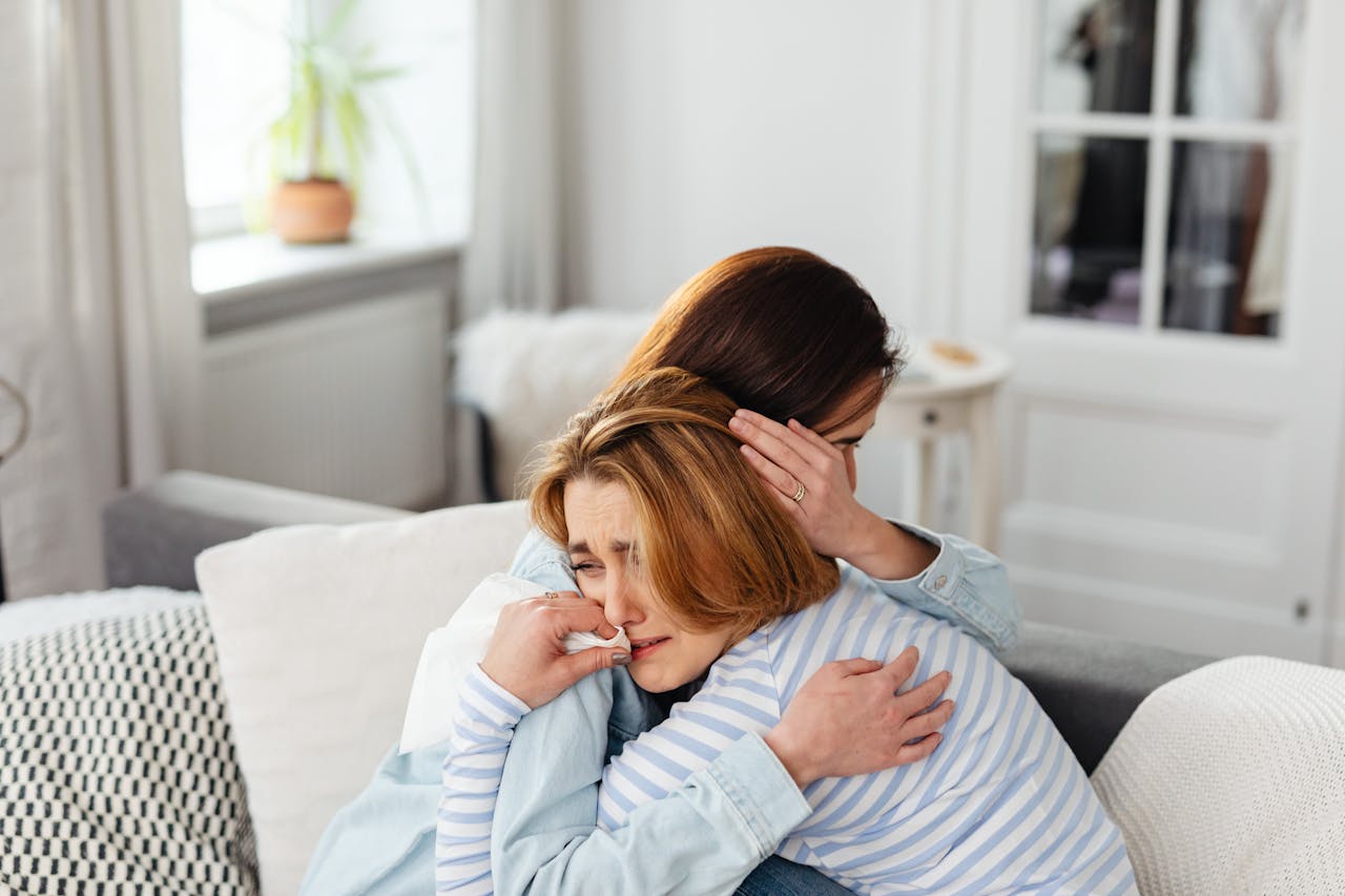 Woman crying and hugging another woman.