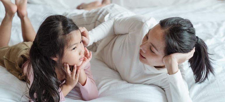 Woman lying on a bed next to a child and helping a child whose parent is struggling with addiction.