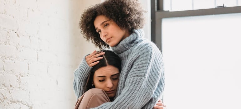 Two women hugging and supporting each other.