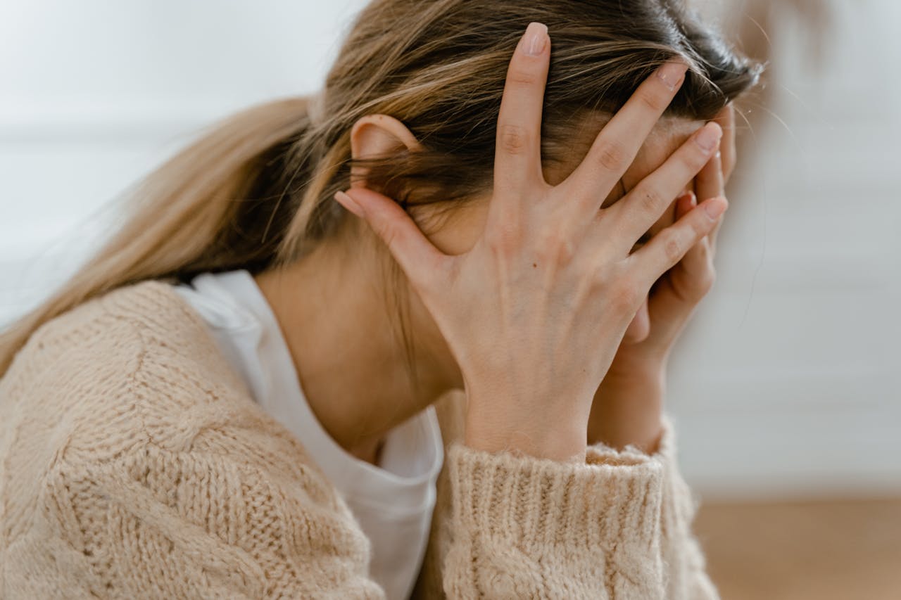 Woman covering her face with her hands.