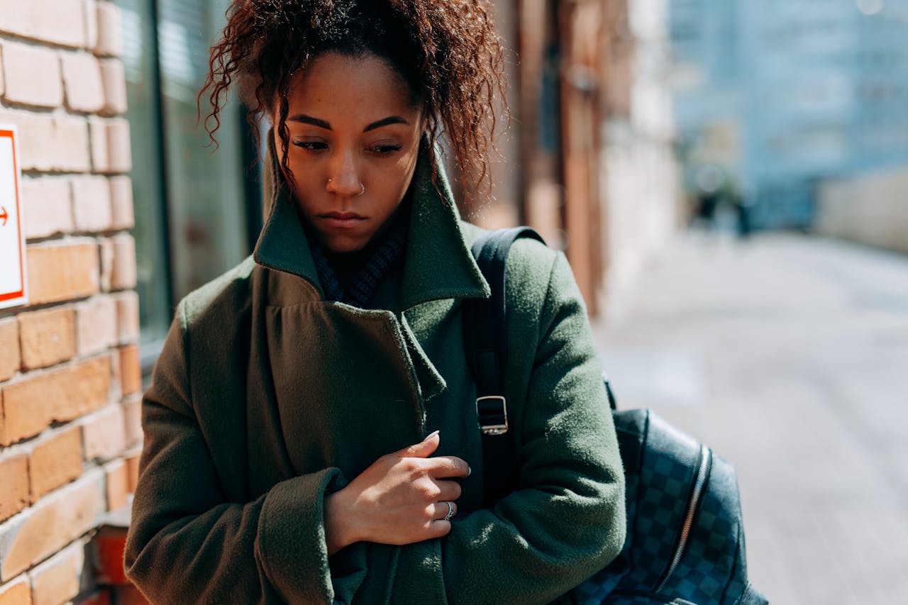 Woman holding her jacket and walking on the street.