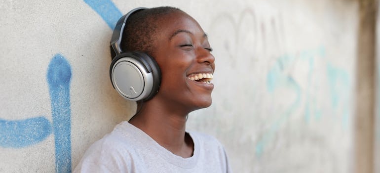 Woman leaning against the wall and listening to music.