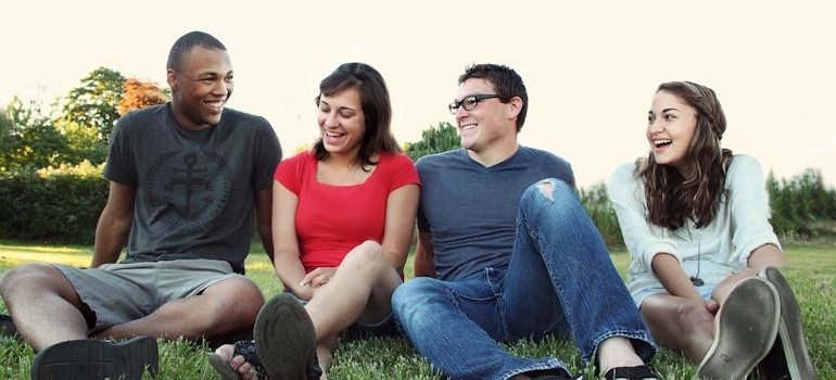 Four friends sitting on the grass laughing and discussing how to stop intrusive thoughts.