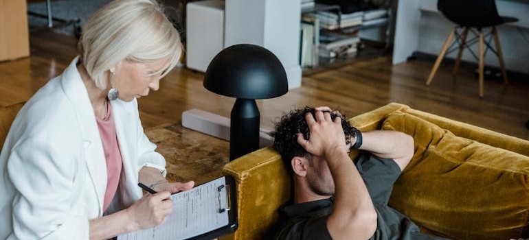 Man holding his head while talking to a therapist.