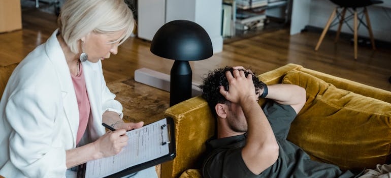 Young man holding his head and talking to his therapist about repairing relationships after addiction.