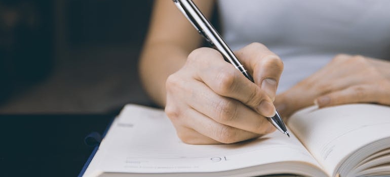 Woman writing her long term sobriety goals in a notebook.