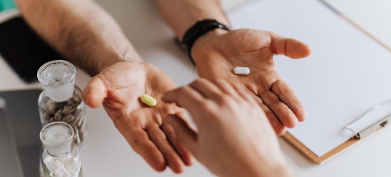 Doctor handing a patient two pills to help with Ecstasy and PTSD problems.