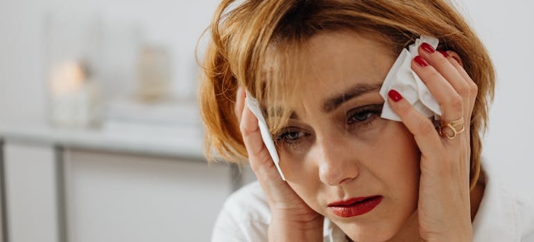 Woman crying and holding tissues next to her face while struggling with Ritalin side effects in females.