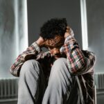 Man sitting on the floor and covering his ears.