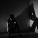 Person sitting on the floor in a dark room.