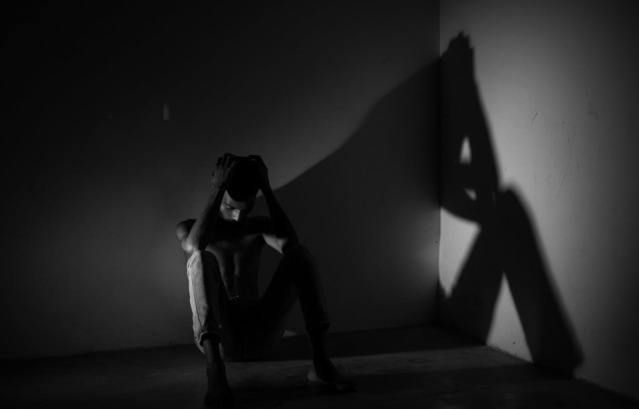 Person sitting on the floor in a dark room.