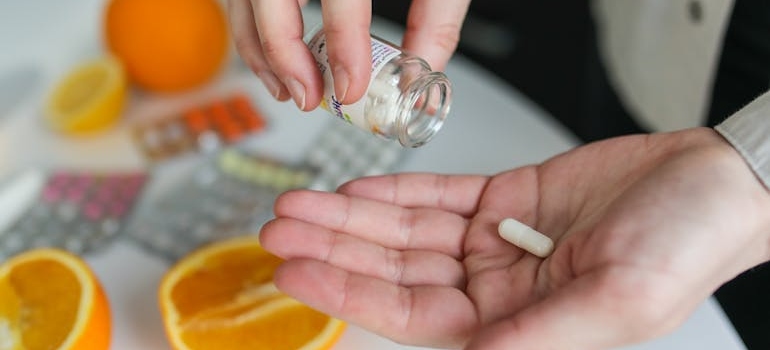 Person putting a supplement pill in their hand.