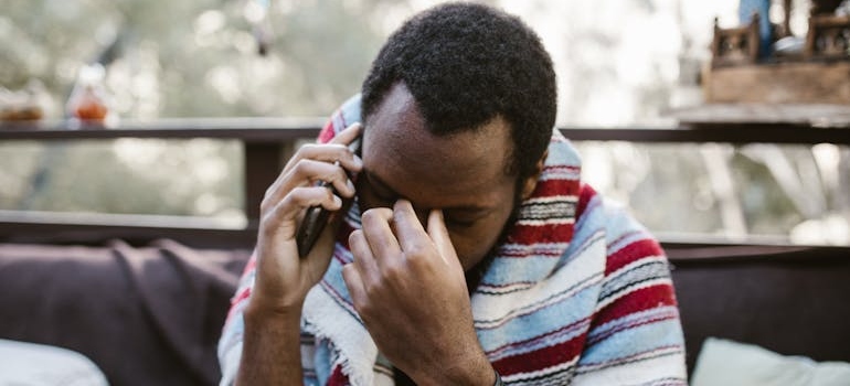 Man crying and calling a helpline.