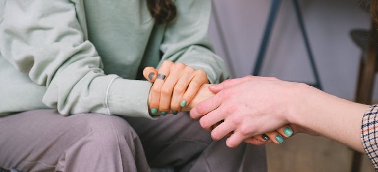 Woman holding another woman's hand and supporting her through Ecstasy and PTSD problems.