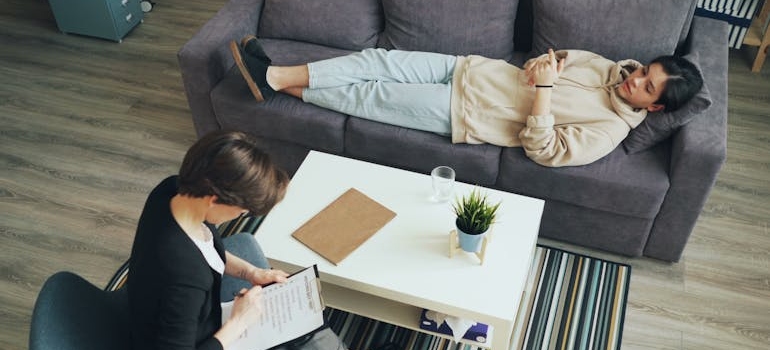 Woman lying on the couch and talking to her therapist about the cycle of addiction.