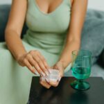 Woman sitting on a couch and taking a pill.