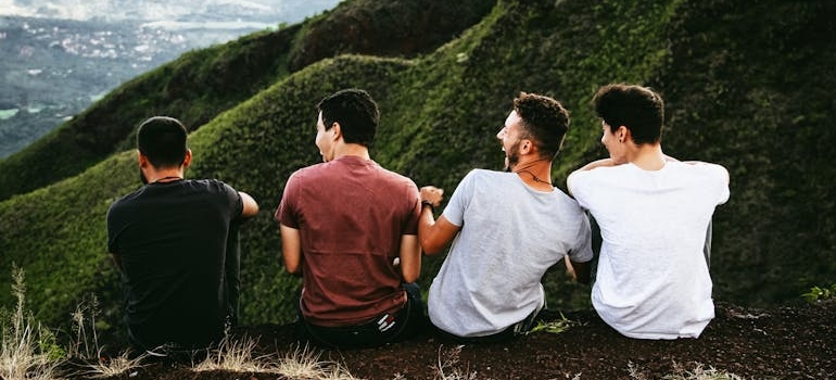 Four men sitting on the ground and laughing.