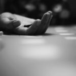 Person's hand on the floor holding pills.