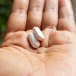 Person holding two pills in their hand.