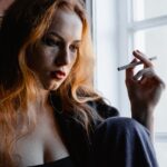 Woman sitting by the window and smoking a cigarette.