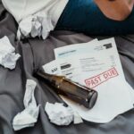 Bills and alcohol bottles on a bed.