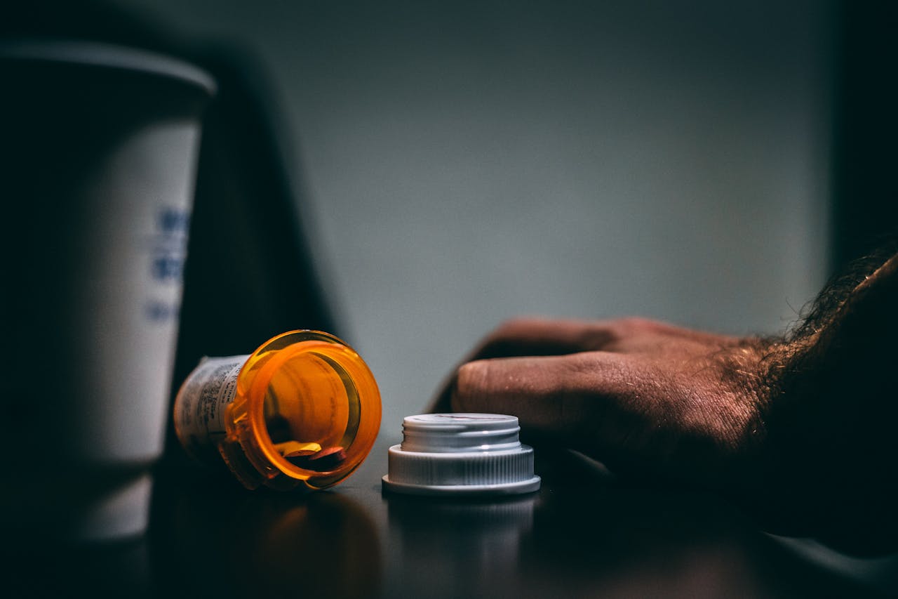 Hand next to a spilled pill bottle.